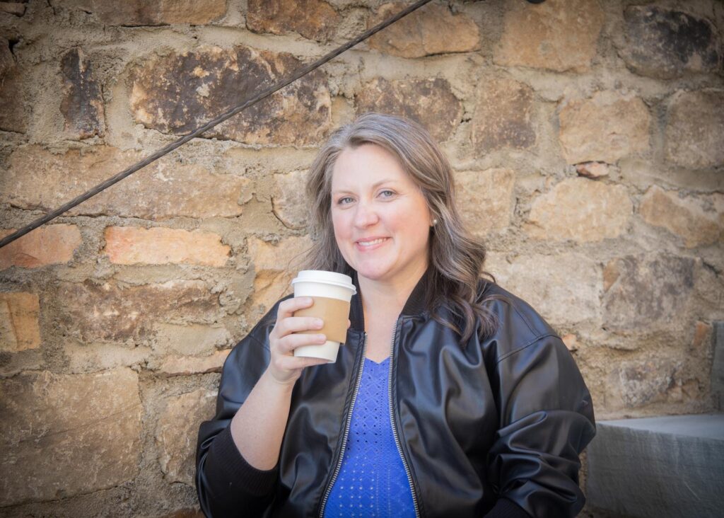 Kate Huff smiling and holding a cup of coffee