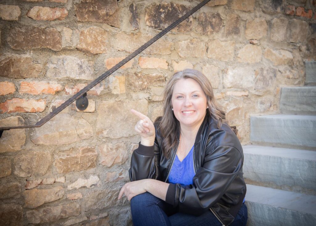 Kate Huff smiling and pointing toward the Book a Call button